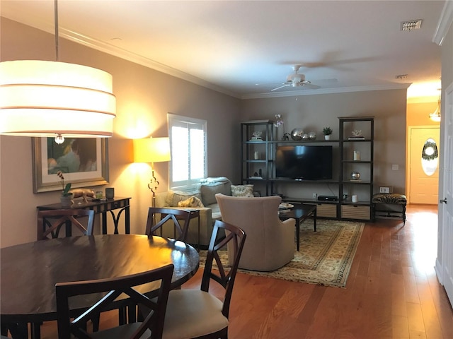 living room with ceiling fan, visible vents, wood finished floors, and ornamental molding