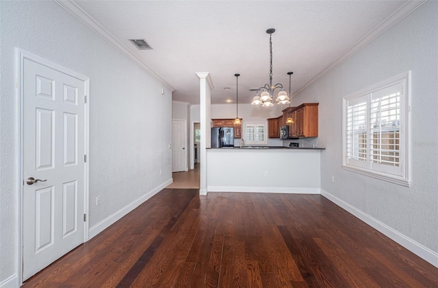 kitchen featuring visible vents, dark wood finished floors, fridge, stainless steel microwave, and brown cabinets