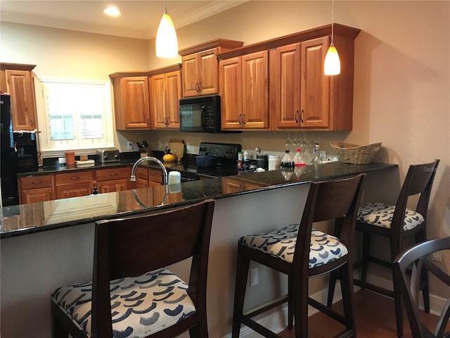 kitchen with hanging light fixtures, black appliances, and a kitchen bar