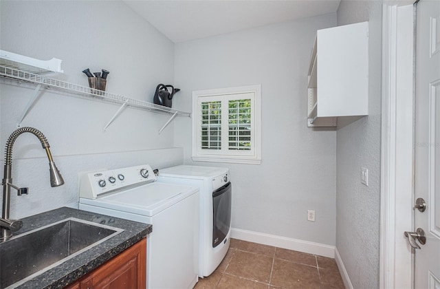 clothes washing area featuring tile patterned floors, a sink, cabinet space, baseboards, and washing machine and clothes dryer