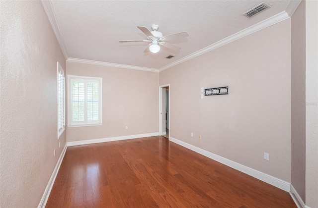 empty room with visible vents, ornamental molding, baseboards, and wood finished floors