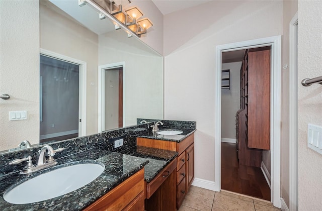 bathroom with a sink, baseboards, double vanity, and tile patterned floors