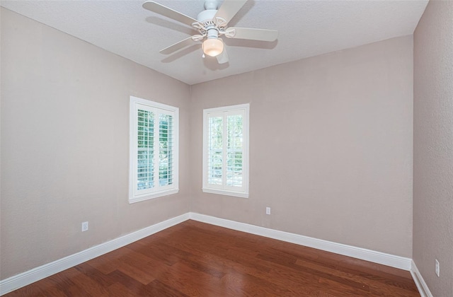 unfurnished room featuring dark wood-style floors, ceiling fan, a textured ceiling, and baseboards