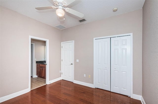 unfurnished bedroom featuring visible vents, baseboards, wood finished floors, a closet, and a textured ceiling