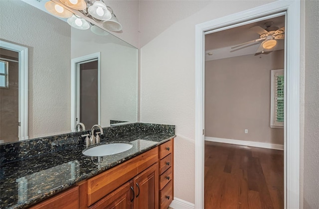 bathroom with a ceiling fan, vanity, wood finished floors, and baseboards