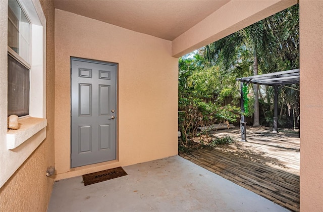 view of exterior entry with stucco siding and a patio