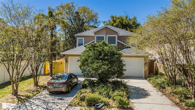 traditional-style house with stucco siding, driveway, and fence