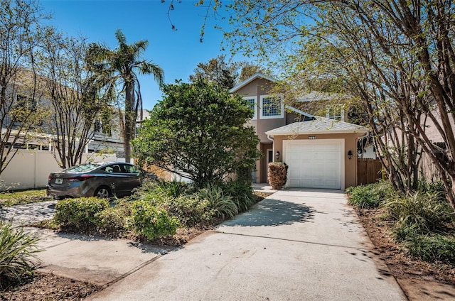 view of front facade featuring an attached garage, fence, driveway, and stucco siding