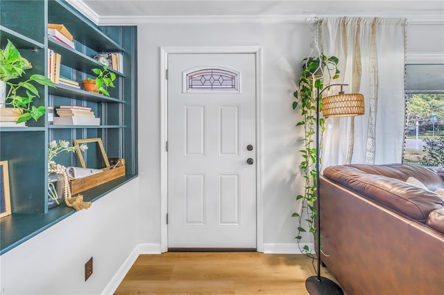 foyer featuring crown molding, baseboards, and wood finished floors