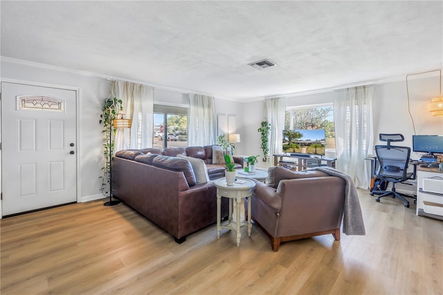 living room with visible vents, light wood-style flooring, a textured ceiling, and baseboards