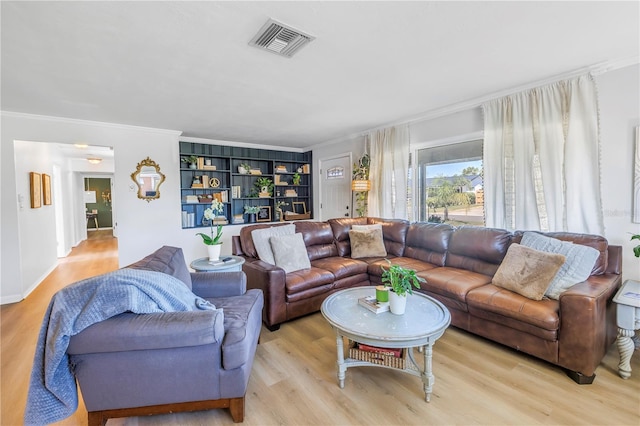 living room featuring light wood-style flooring, built in shelves, visible vents, and ornamental molding