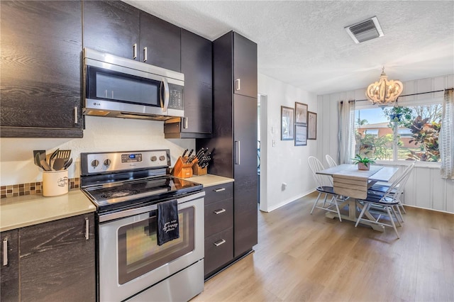 kitchen featuring visible vents, light wood-style flooring, a textured ceiling, stainless steel appliances, and light countertops