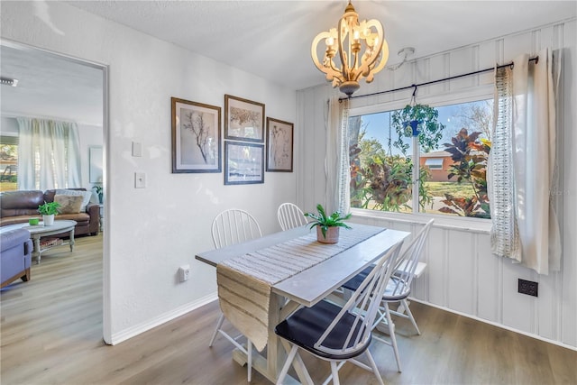 dining area featuring a chandelier, plenty of natural light, and wood finished floors