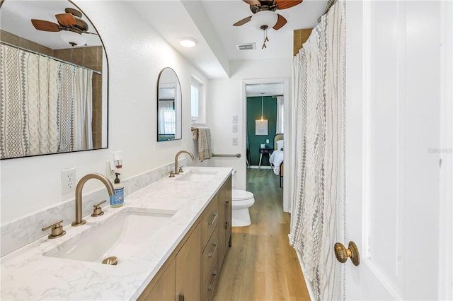 full bathroom with double vanity, wood finished floors, visible vents, and a sink