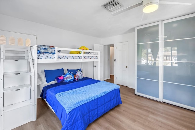 bedroom with ceiling fan, visible vents, and wood finished floors