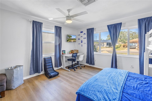 bedroom with ceiling fan, visible vents, baseboards, and wood finished floors