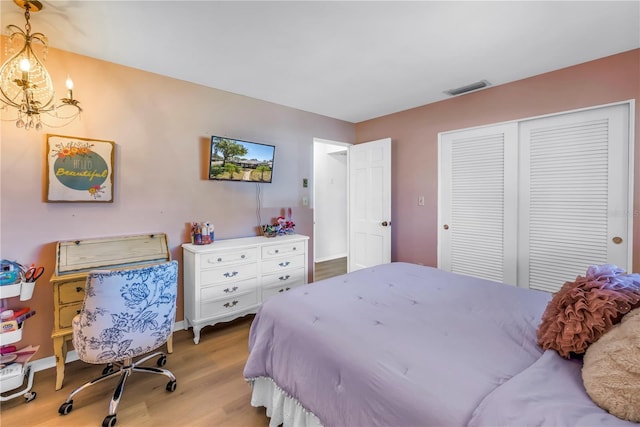 bedroom featuring visible vents, baseboards, an inviting chandelier, wood finished floors, and a closet