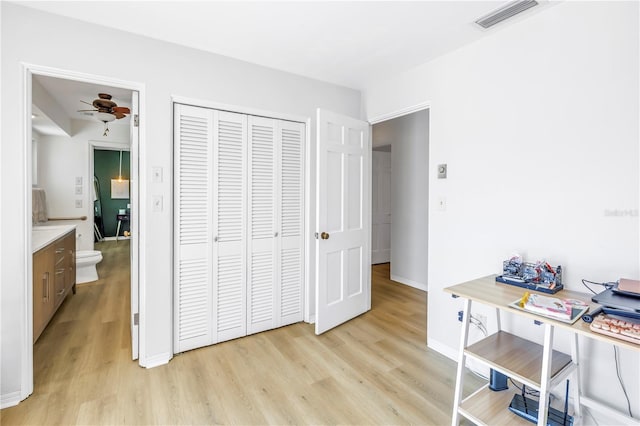 bedroom with light wood finished floors, visible vents, baseboards, and a closet