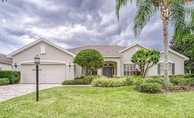 ranch-style home with stucco siding, driveway, an attached garage, and a front yard