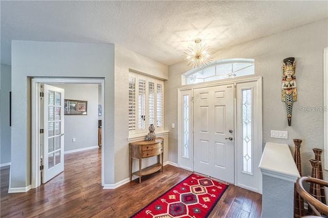 entrance foyer with hardwood / wood-style floors, a healthy amount of sunlight, baseboards, and a textured ceiling