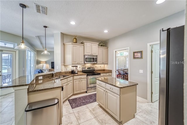 kitchen featuring visible vents, appliances with stainless steel finishes, a peninsula, and dark stone counters