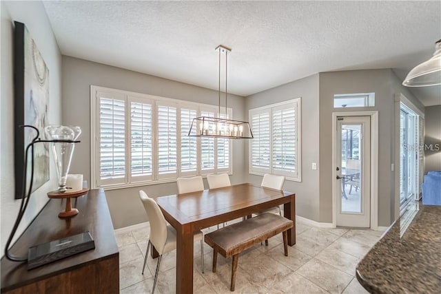 dining space with baseboards, a textured ceiling, an inviting chandelier, and light tile patterned flooring