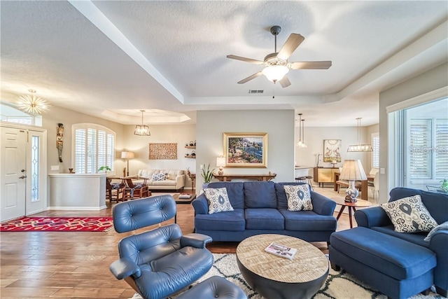 living room with visible vents, a ceiling fan, a textured ceiling, wood finished floors, and a raised ceiling