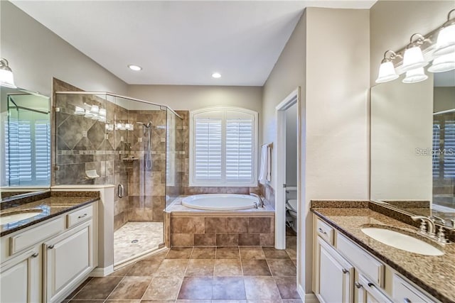 full bath featuring a shower stall, toilet, two vanities, a bath, and a sink