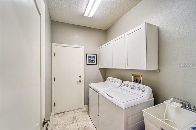 washroom featuring washing machine and clothes dryer, cabinet space, a sink, a textured ceiling, and a textured wall