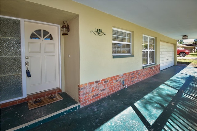 property entrance with stucco siding and a garage