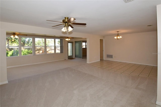 spare room featuring plenty of natural light, light colored carpet, ceiling fan with notable chandelier, and visible vents