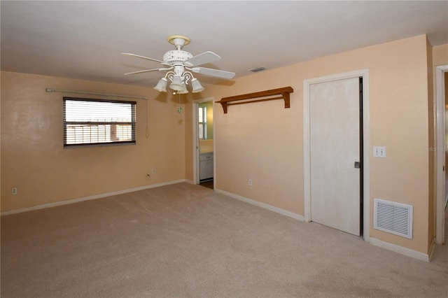 unfurnished room featuring light colored carpet, a ceiling fan, visible vents, and baseboards