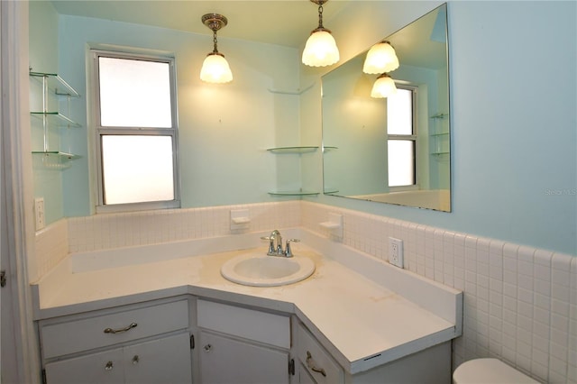 bathroom featuring toilet, vanity, and tile walls