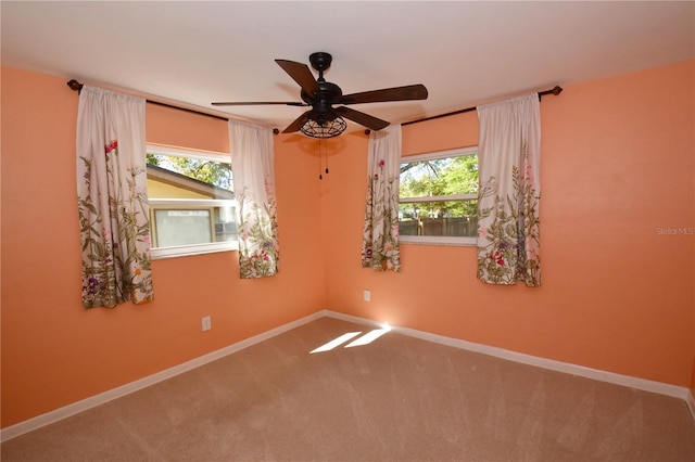 carpeted spare room with baseboards, plenty of natural light, and a ceiling fan