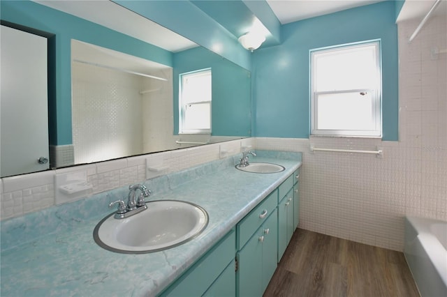 bathroom featuring double vanity, wood finished floors, tile walls, and a sink