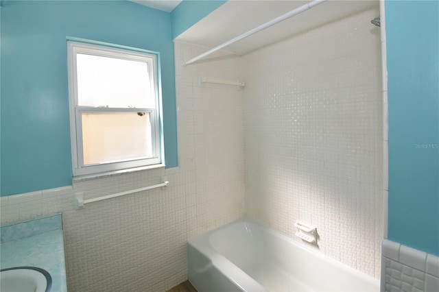 bathroom featuring tile walls and bathing tub / shower combination