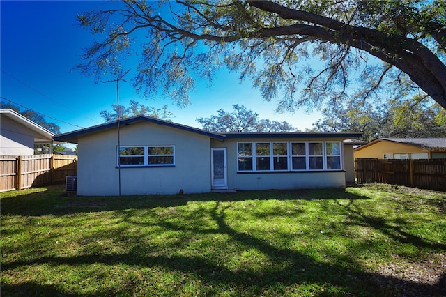 back of house with stucco siding, a lawn, and a fenced backyard