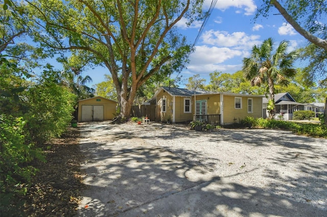 view of front of property featuring a detached garage, fence, an outdoor structure, and a shed