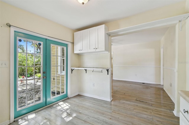 clothes washing area with light wood-style flooring, french doors, and baseboards