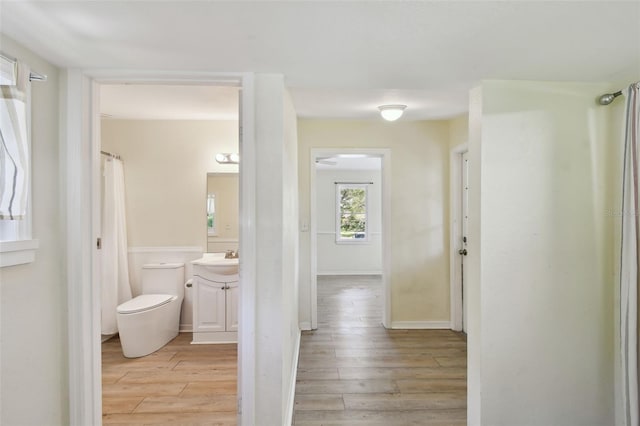 hallway with a sink, baseboards, and light wood-style flooring