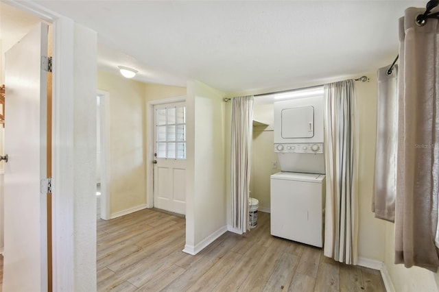 laundry room with laundry area, stacked washer and dryer, baseboards, and light wood finished floors