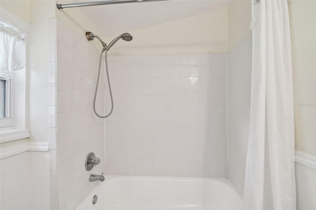 bathroom with shower / tub combo and a wainscoted wall