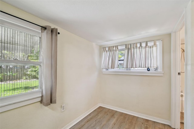 unfurnished room with baseboards, a healthy amount of sunlight, and wood finished floors