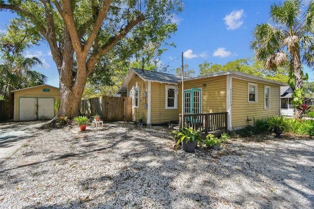 view of front facade featuring french doors, a detached garage, an outdoor structure, and fence