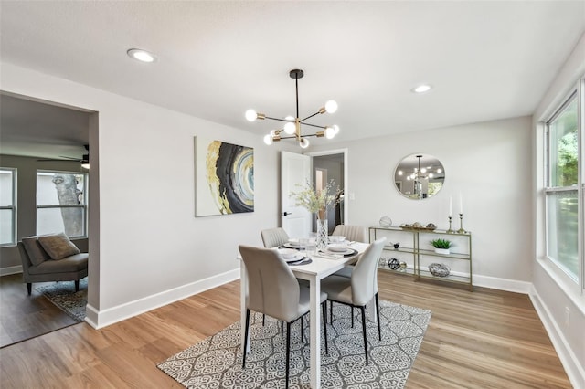 dining space featuring baseboards, light wood-type flooring, and an inviting chandelier