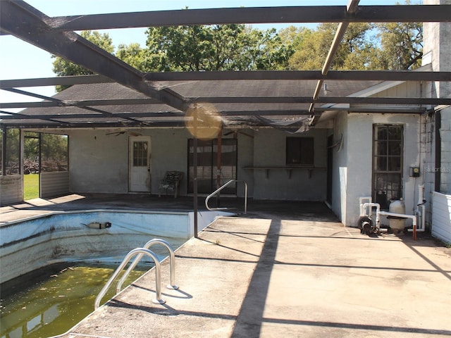 view of swimming pool with ceiling fan, an empty pool, a lanai, and a patio area