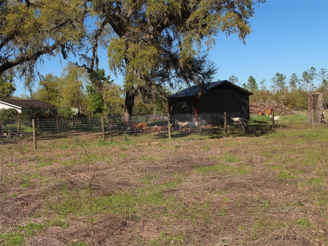 view of yard with an outbuilding, a rural view, a pole building, and fence