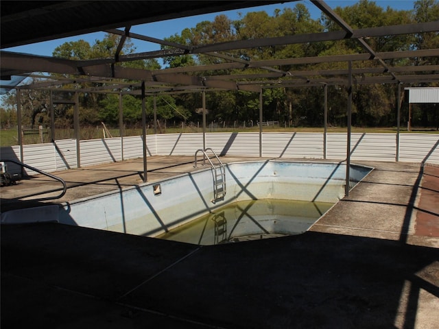 view of pool with glass enclosure, a patio, and an empty pool