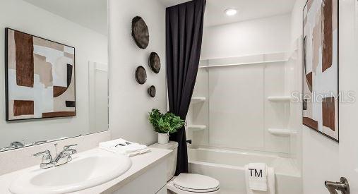 bathroom featuring shower / bath combo with shower curtain, toilet, and vanity