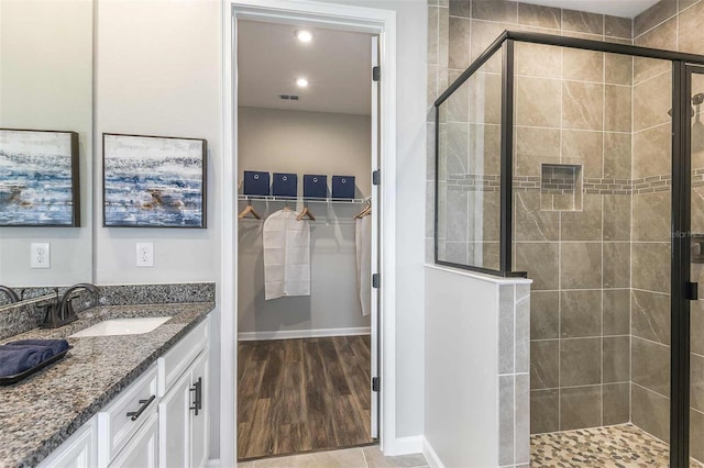 bathroom with vanity, baseboards, visible vents, a shower stall, and a walk in closet